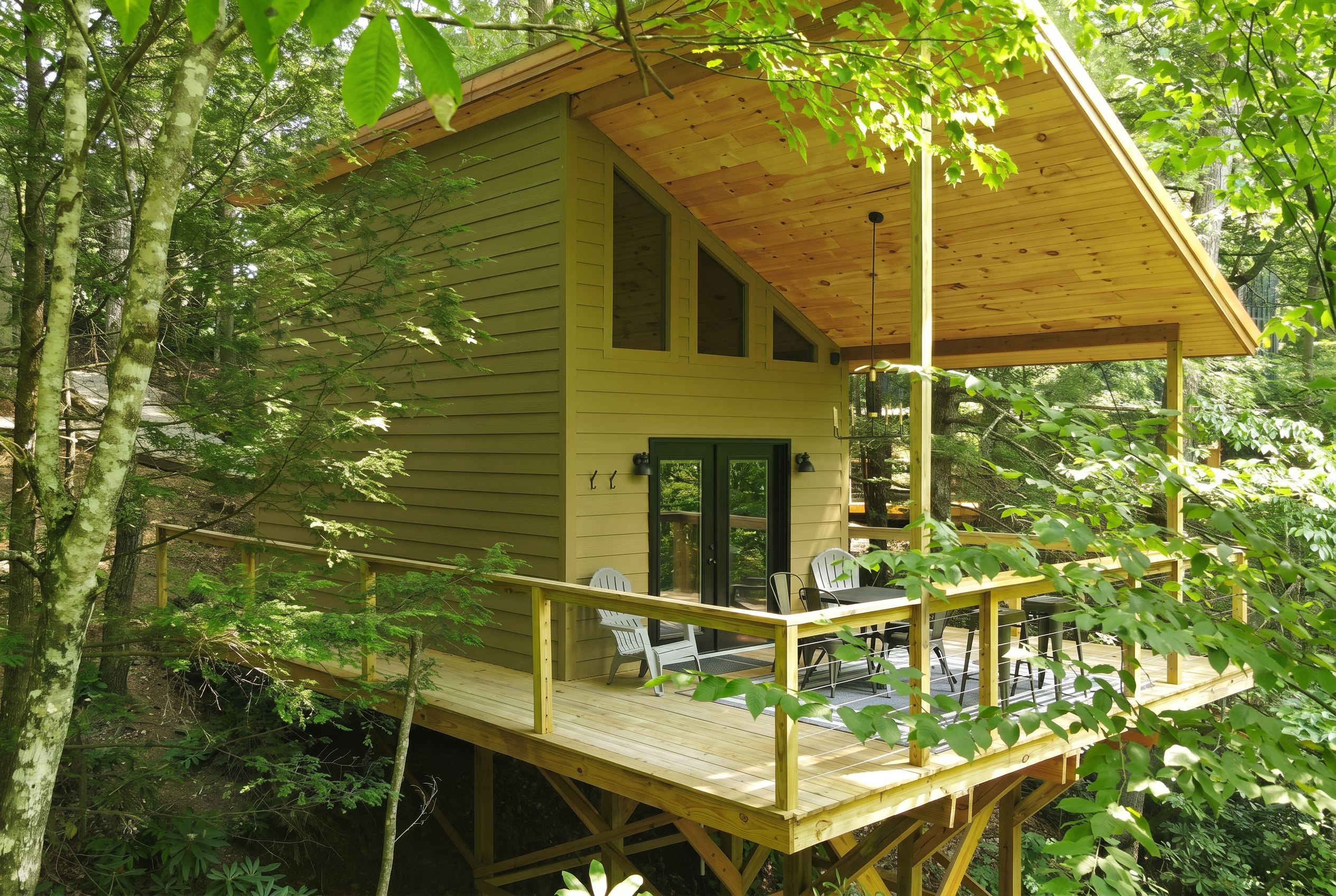 Treehouse-style cottage on stilts with a large covered deck among green trees
